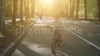 在柏油路骑自行车的快乐男孩。 可爱的男孩在自行车道上学骑自行车。